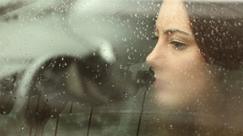 Depressive Frau schaut aus dem Fenster